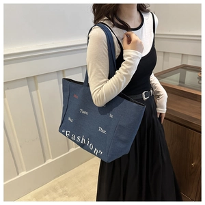 Detail of blue denim tote bag with vintage Fashion print worn by a model in a casual setting