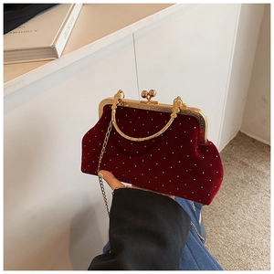 Close-up of wine red velvet shell bag with pearl decor and golden metal handle