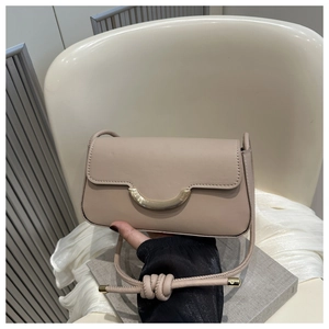 Detail of beige small crossbody bag with gold arch buckle and knotted strap accents