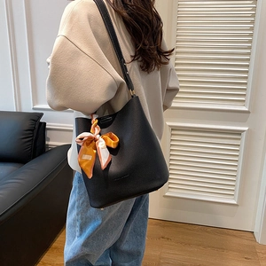 Sac seau noir minimaliste à texture lychee orné d'un foulard en soie et pieds en métal