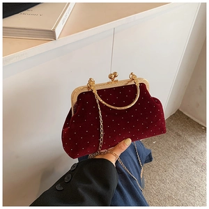 Detail of burgundy velvet shell bag with white pearls and gold metal handle and chain