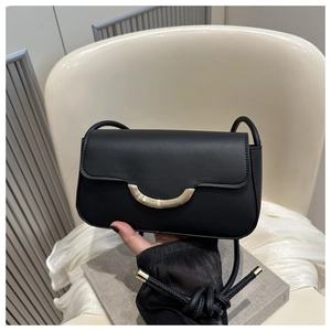 Close-up of black matte leather crossbody bag with a distinctive gold semicircular buckle