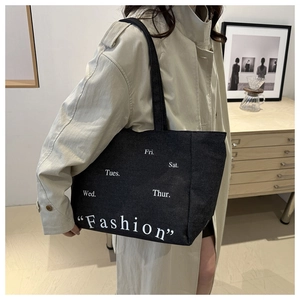 Detail of black canvas tote bag featuring Fashion print and white weekday text