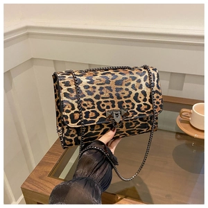 Close-up of leopard print crossbody bag with metal chain on a cozy cafe table setting