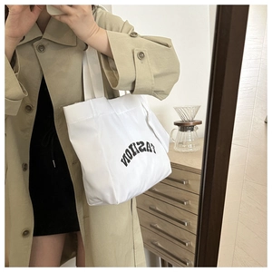 Detail of white canvas tote bag with inverted FASHION print in a mirror selfie view