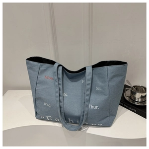 Detail of blue denim tote bag with red and white fashion typography on minimalist stand