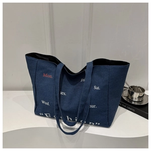 Macro view of blue denim tote bag with red Mon. print and white fashion lettering