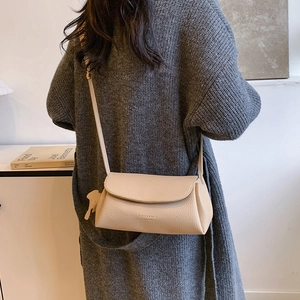 Minimalist beige crossbody bag with textured leather and a cute animal charm shown on model