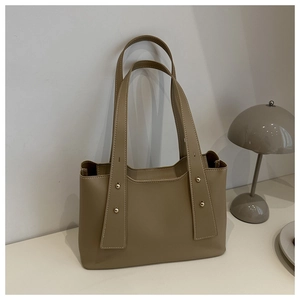 Detail view of khaki PU tote bag featuring wide shoulder straps and metallic stud accents