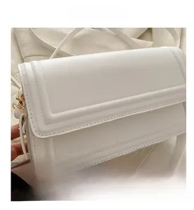 Détail rapproché du sac à rabat en cuir blanc avec finitions dorées et surpiqûres