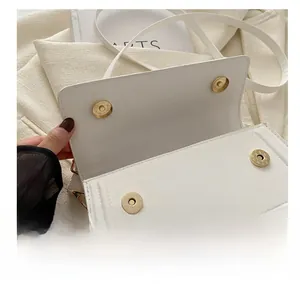 Détail de sac bandoulière en cuir blanc montrant les boucles magnétiques dorées et la texture