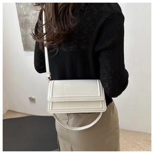 Vue arrière d'un sac bandoulière blanc rectangulaire avec texture à paliers sur modèle