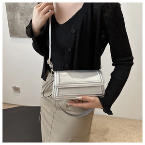 Sac bandoulière carré argenté métallisé porté par un mannequin dans un style épuré