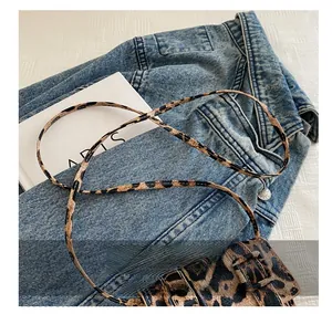 Detail of mini leopard print crossbody bag with slim strap on denim jacket background