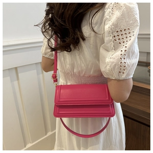 Détail du sac bandoulière rectangulaire fuchsia avec rayures texturées et boucles dorées
