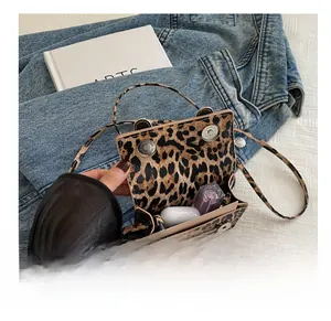 Interior view of leopard print crossbody bag holding lipstick and wireless earbud case