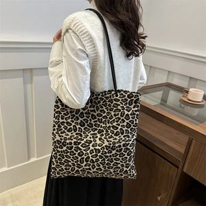Fashionable leopard print canvas tote bag with slim black straps on a casual model