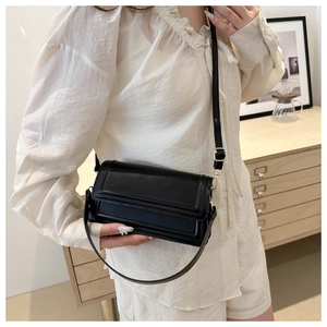 Détail d'un sac bandoulière minimaliste en cuir noir mat avec des détails dorés