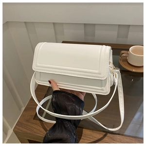 Gros plan d'un sac bandoulière blanc en cuir PU avec surpiqûres et boucle dorée