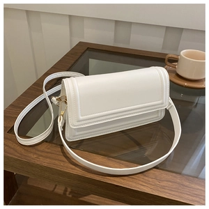 Détail du sac bandoulière blanc avec texture géométrique gaufrée et finitions dorées chic