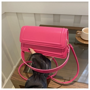 Détail du sac bandoulière en cuir rose vif avec rabat et finitions métalliques dorées