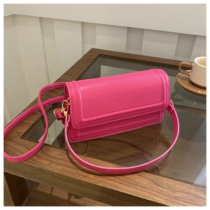 Détail d'un sac bandoulière en cuir magenta avec motif géométrique en relief sur table