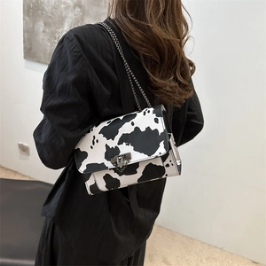 Chic black and white cow print crossbody bag with metal chain strap and unique clasp