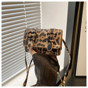 Close-up of leopard print crossbody bag with dual square buckles and retro flap design