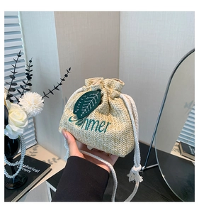 Detail of straw bucket bag with Summer embroidery and green leaf appliqué accents