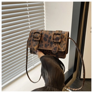 Detail shot of mini leopard print crossbody bag with dual buckles and leather texture