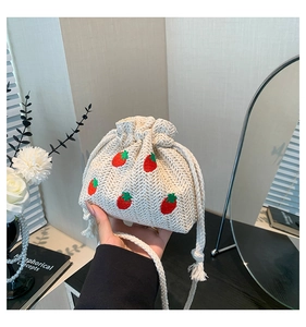 Close-up of woven straw bucket bag with red strawberry embroidery and drawstring closure