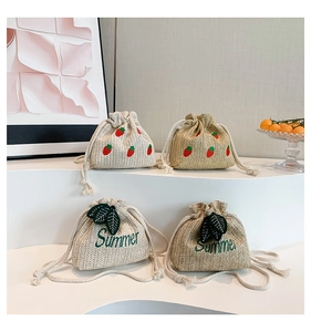 Detail of handmade straw bucket bags featuring strawberry and Summer leaf embroidery