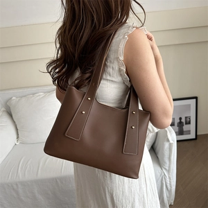 Brown leather bucket bag for women with white contrast stitching and gold rivets