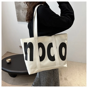 Détail du grand sac cabas crème avec inscription noco et doubles bandoulières solides