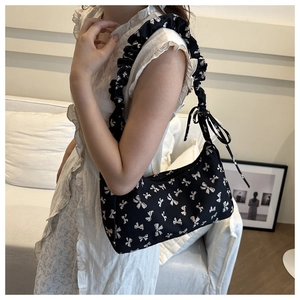 Floral shoulder bag with ruffled straps and white bow print on a black crescent body