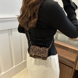 Mini leopard print crossbody flap bag with dual decorative buckles worn by model