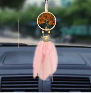 Detail view of life tree car charm with pink feathers and amber stones on rearview mirror
