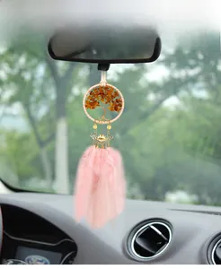 Detail of pink feather car pendant with life tree and golden lotus hanging on rearview mirror