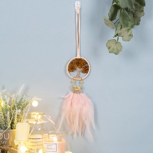 Pink feather dream catcher with tree of life stones and gold charms on blue wall