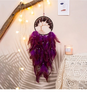 Detail of purple dream catcher with tree of life design and soft feathers hanging on branch