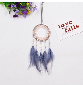 Detalle de atrapasueños con cuentas rosas, plumas grises y tarjeta decorativa