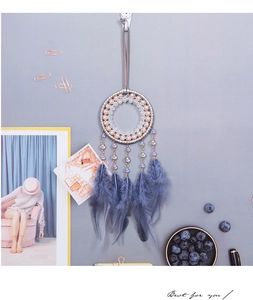 Vista de detalle de atrapasueños con plumas azules y cuentas rosas en gancho blanco