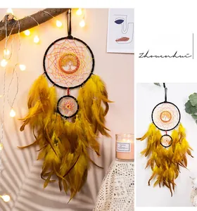 Yellow Tree of Life dreamcatcher with soft feathers and red beads in warm home setting