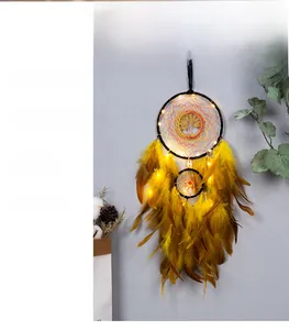 Detail of dream catcher wall hanging with warm LED lights and bright yellow feathers