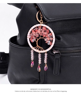 Detailed handmade tree of life keychain with pink crystals on a black leather bag