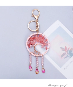 Macro shot of pink crystal Tree of Life keychain with teardrop charms on purple background