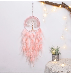 Pink dreamcatcher with tree of life design and soft feathers on a warm home wall