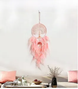 Pink Tree of Life dreamcatcher with soft feathers hanging in a cozy living room setting