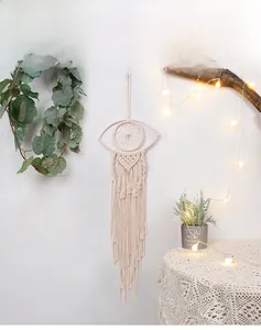 Detail of bohemian eye-shaped woven wall hanging with cotton fringe in cozy interior