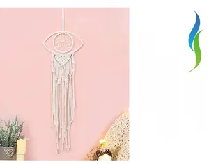 Detail of bohemian eye macrame wall hanging with woven cotton fringe and warm lighting